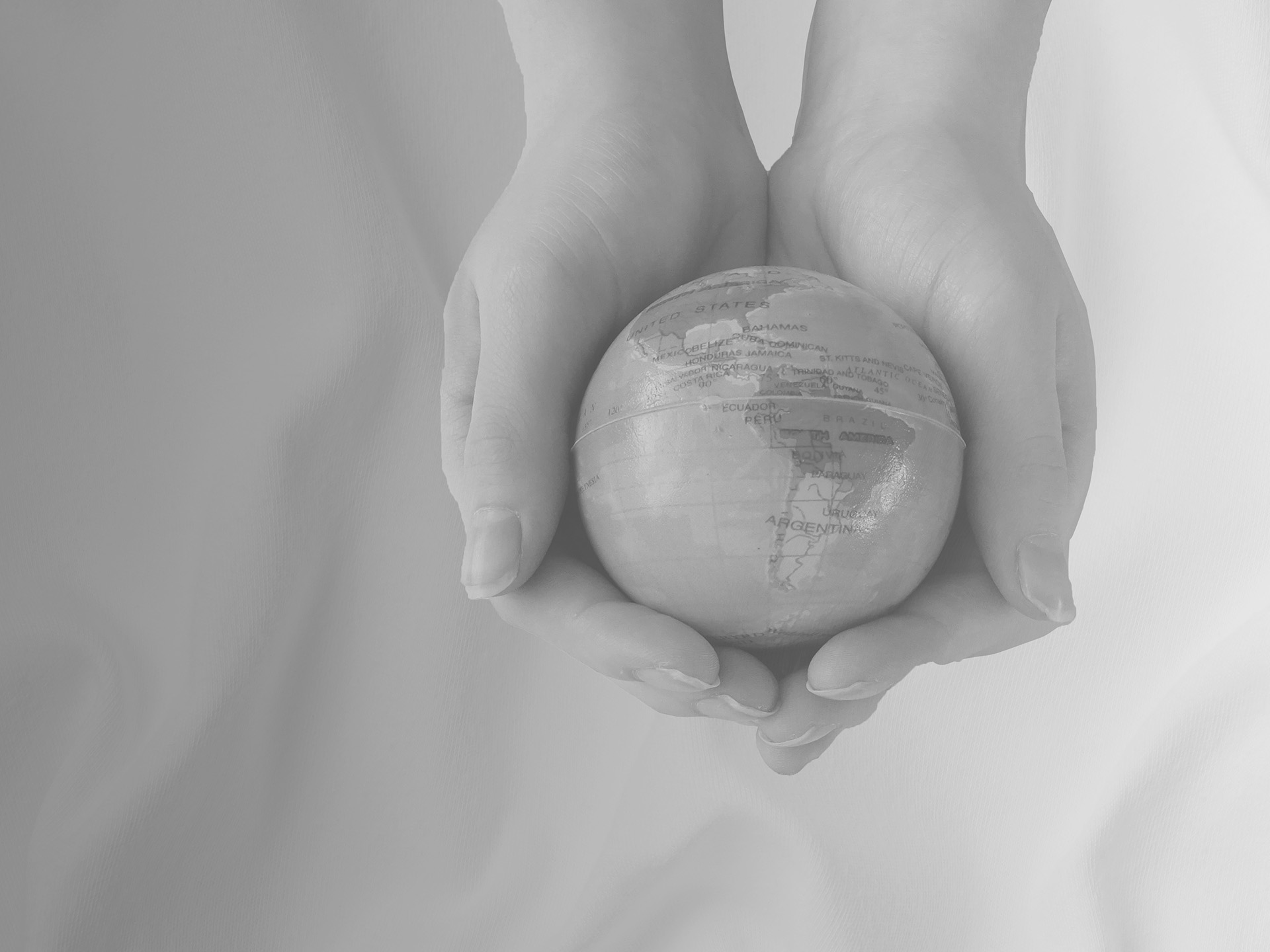 Two hands holding a small globe